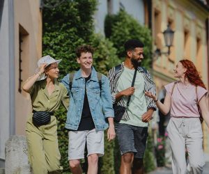Group of four recent graduates walking and smiling together