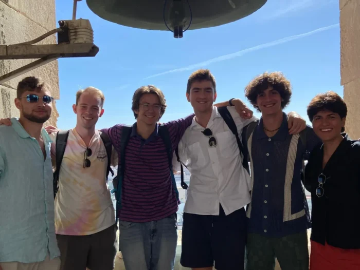 Group of smiling interns posing together outdoors on a sunny day.