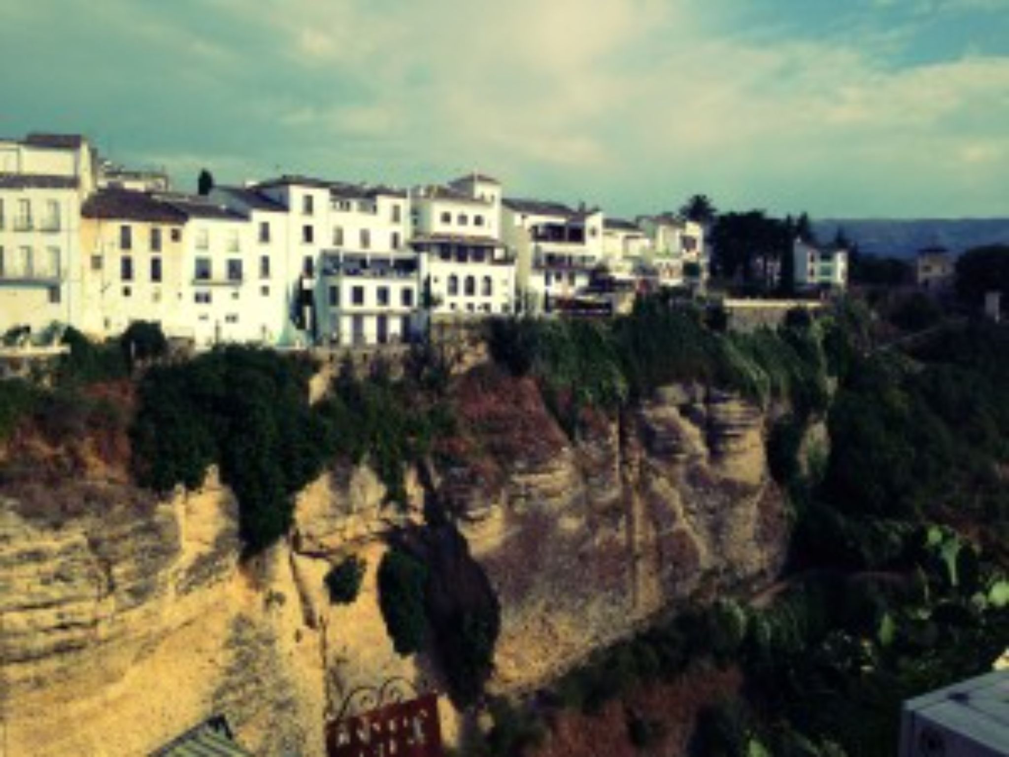 White buildings on cliffside in Marbella under cloudy sky.