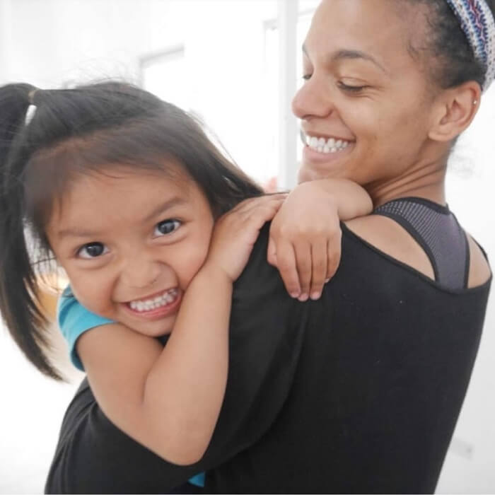 Woman smiling while holding a young girl who is grinning at the camera