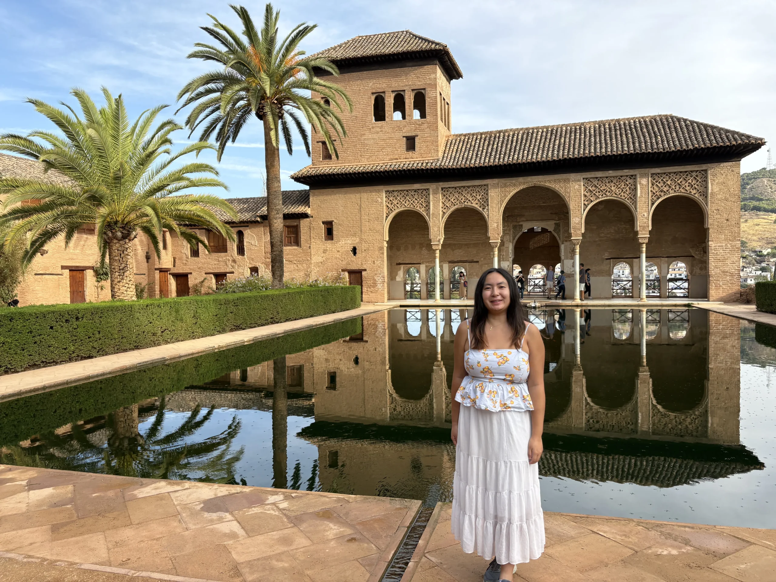 Student posing in front of the Alhambra Palace reflecting pool during a Granada excursion in Spain