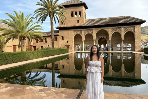 Student posing in front of the Alhambra Palace reflecting pool during a Granada excursion in Spain