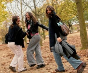 Three female students laughing together in a park
