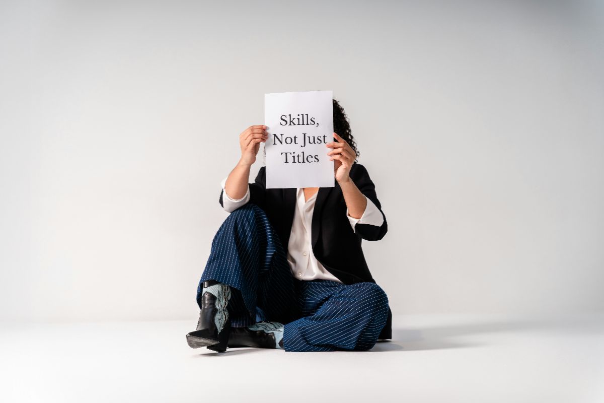 Woman holding a sign reading Skills Not Just Titles