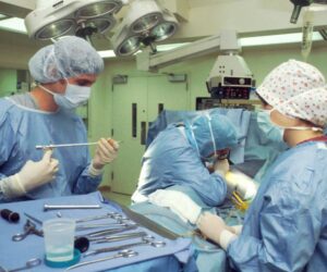 Medical professionals performing a surgical procedure in an operating room.