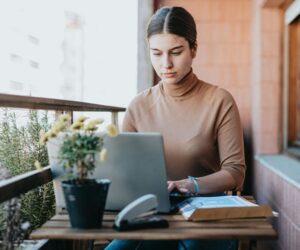 Focused woman on a European balcony using a laptop