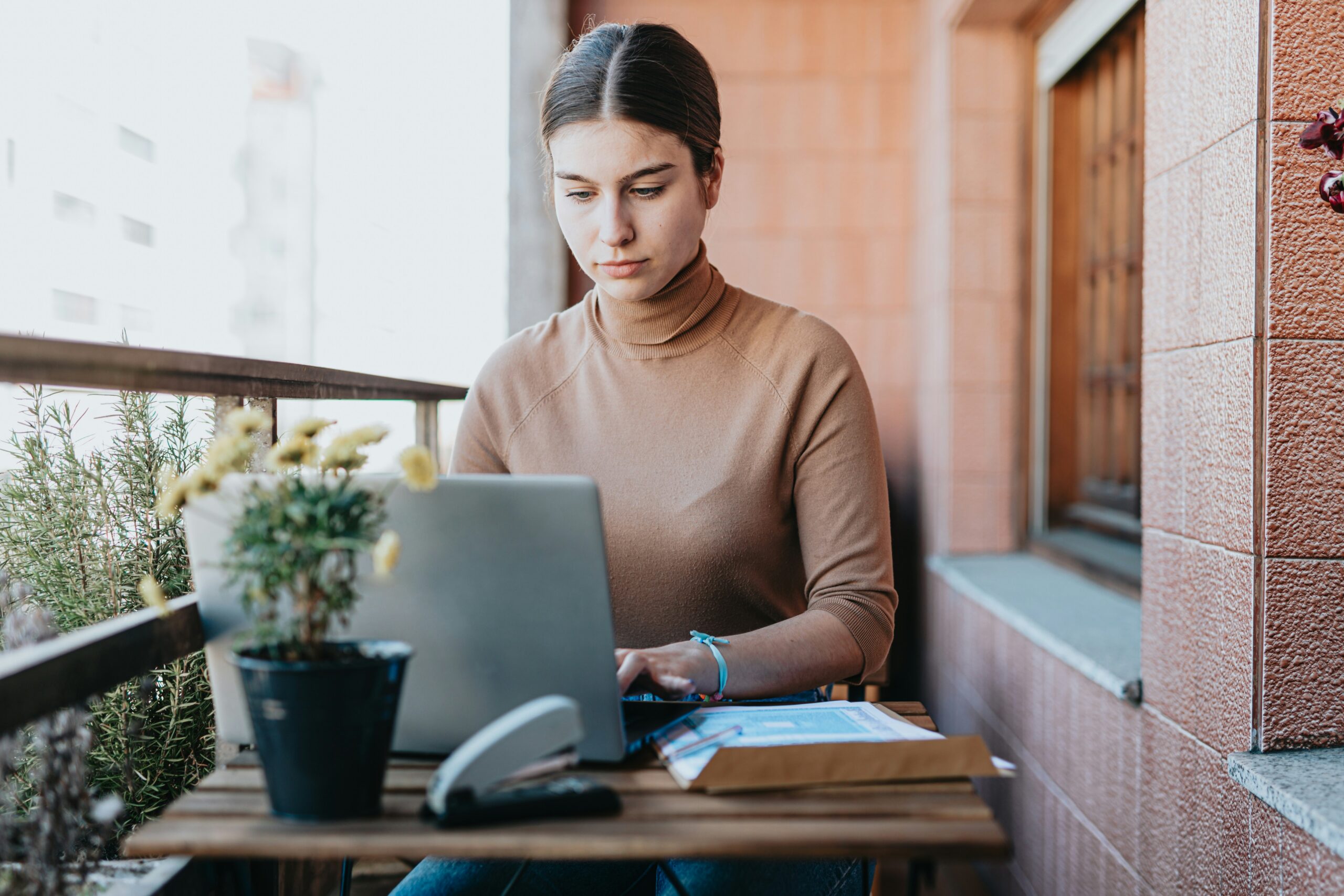 Focused woman on a European balcony using a laptop