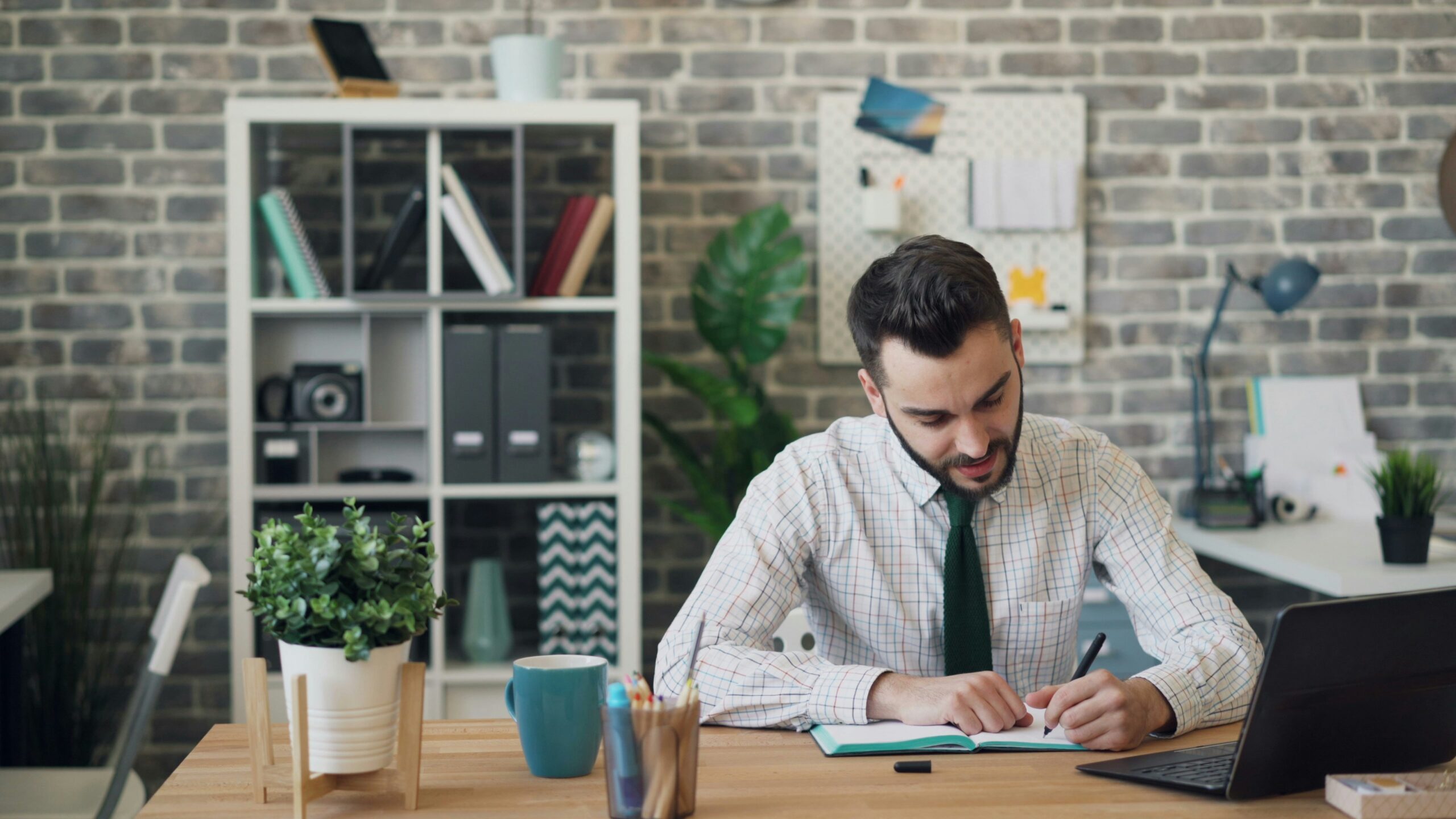 Candidate writing in a notebook next to a laptop during interview preparation