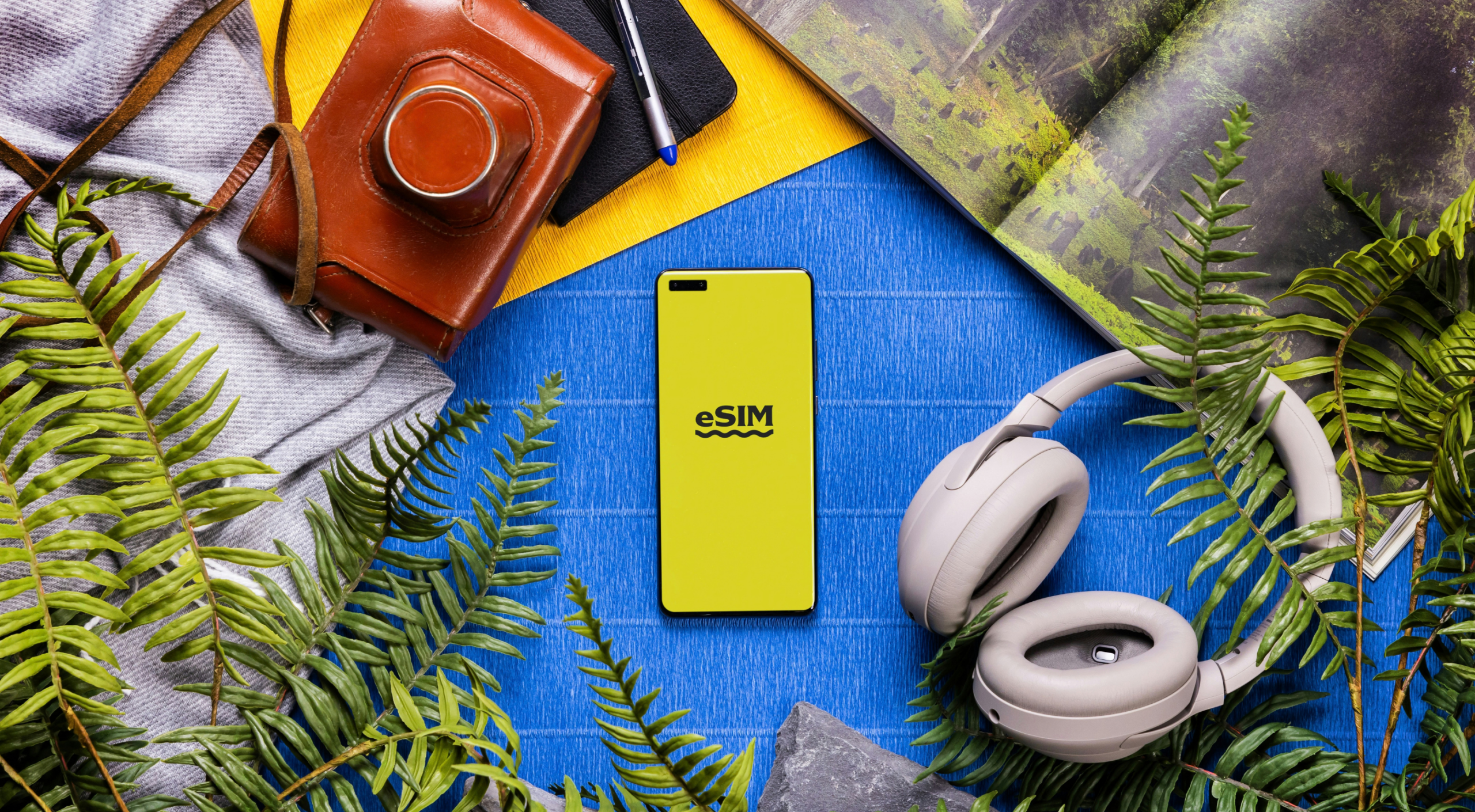 Smartphone displaying an eSIM text on screen surrounded by travel accessories